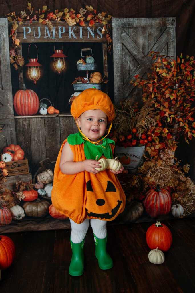 Toddler in pumpkin costume at Palatine Halloween event at Just Peachy Photography studio
