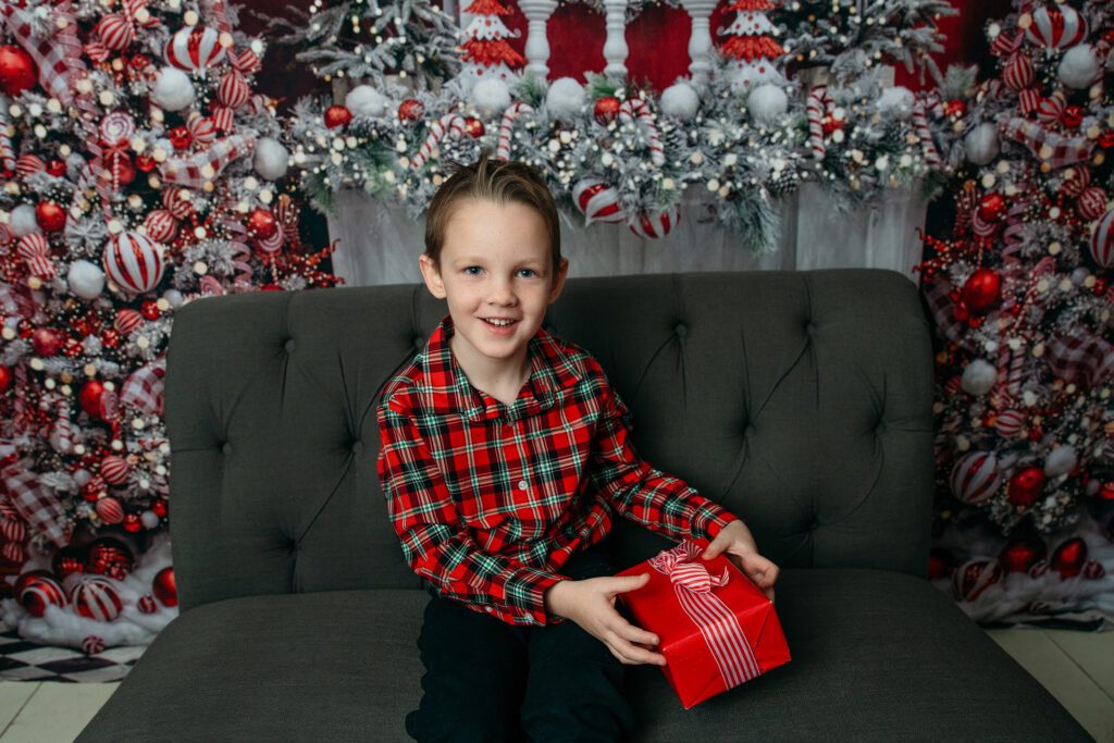 boy smiles with present at holiday family photo session with Just Peachy Photography in Palatine, IL 